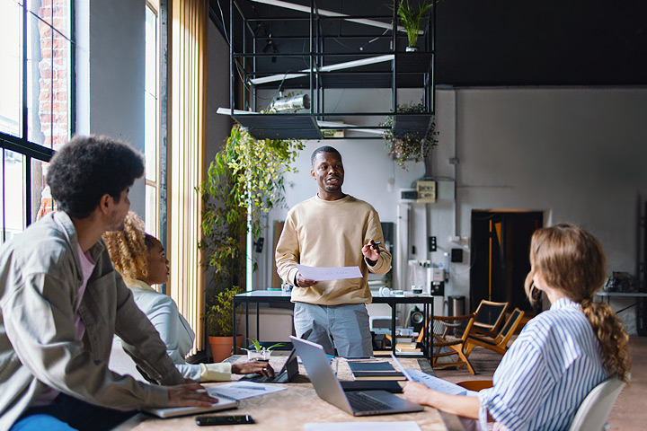 office workers discuss strategies around a desk in a modern workspace